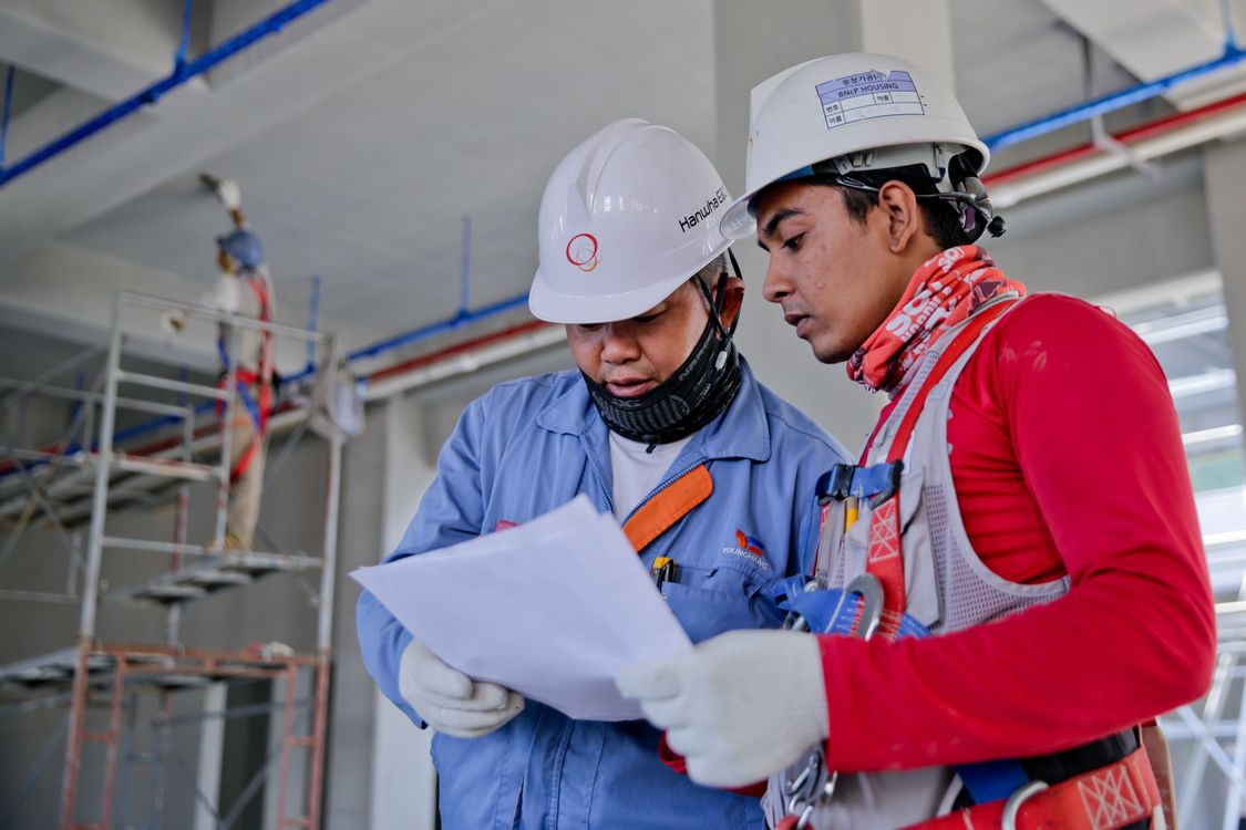 Engineers reviewing plans beside a bridge